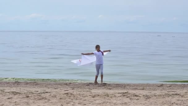 Flicka viftande flagga de olympiska spelen utomhus över molnig himmel och blått vatten i havet. Ett sportfan för barn. 27.06.2020 Sankt Petersburg Ryssland — Stockvideo