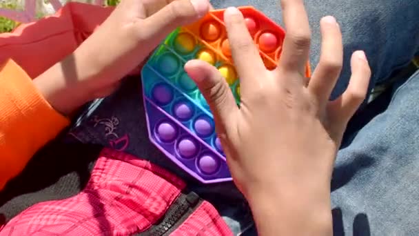 五颜六色的抗压力感官玩具坐立不安推着它在孩子们的手里。弹出它玩具 — 图库视频影像