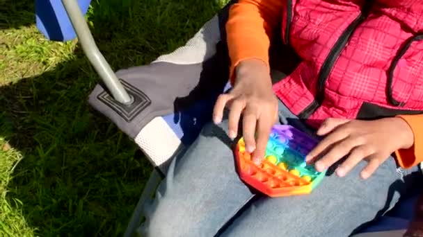 Πολύχρωμο αντιαγχωτικό αισθητήριο παιχνίδι fidget push pop αυτό σε παιδιά χέρια. Πέτα το παιχνίδι. — Αρχείο Βίντεο