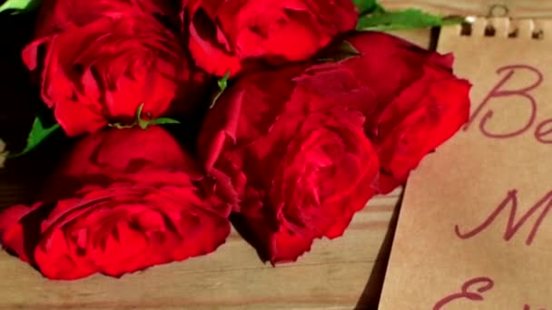 Червоні троянди і бажання матері на дерев'яному фоні . — стокове відео