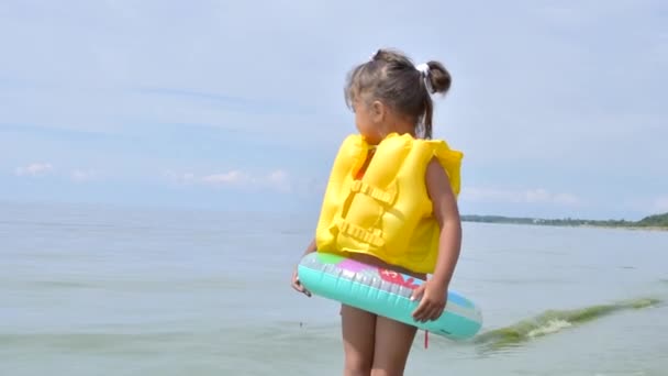 Beztroska dziewczynka w letni weekend. Atrakcje letnie lub przygoda na morzu. Zabawna szczęśliwa dziewczynka w nadmuchiwanym gumowym kółku — Wideo stockowe
