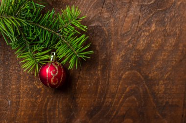 Kırmızı Noel topu yeşil ladin dalına asılmış eski ahşap arka planda. Üst Manzara. Boşluğu kopyala.