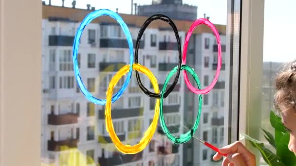 Ragazza che dipinge anelli olimpici sulla finestra durante la quarantena. Russia. 2 maggio 2021. Mosca. — Video Stock