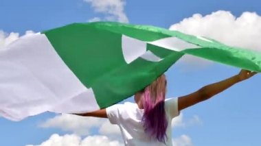 Mavi bulutlu gökyüzü ve altın buğday üzerinde Pakistan bayrağı sallayan bir kız. Pakistan Günü