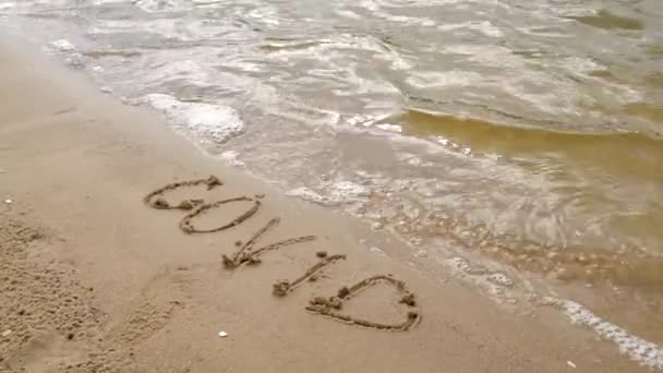 해변의 모래 위에 성찬 문자를 보냈습니다. 바다에 떠 있는 파도가 열렬 한 글을 지운다. 여름철의 관광 규제 철폐, 해변 개방. — 비디오