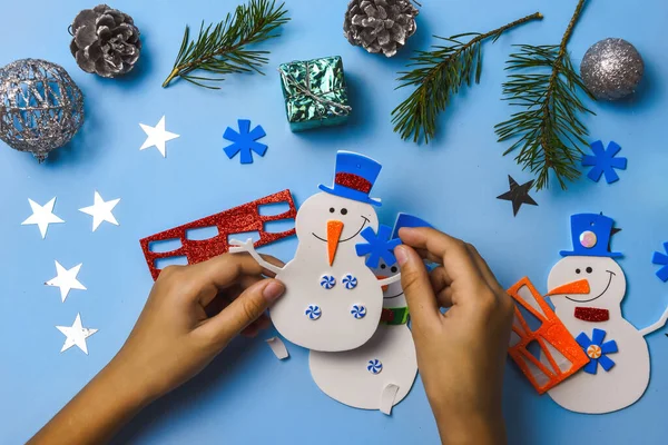 Árvore de Natal ornamentos pendurados. Peças de boneco de neve em fundo de madeira azul. O Natal cria ideias. Vista superior. — Fotografia de Stock