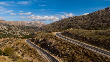 Dönek bir dağ yolu, geniş ve kuru otlarla kaplı yamaçlardan yukarıya doğru tırmanıyor. Uzun bir yolculuk ve manzara..