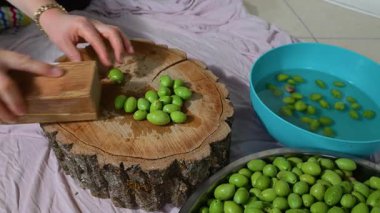 Taze yeşil zeytinler ahşap bir blokta ezilir. Onları tuzlanmaya hazırlamak için geleneksel yöntemler kullanılır. Ev yapımı, organik gıda hazırlama..