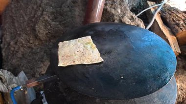 Geleneksel Türk gzme 'si metal bir ızgarada pişirildi. Yemek ahşap bir spatula kullanılarak dönüştürülüyor. Otantik köy yemeği hazırlığı.