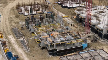 İnşaat işçilerinin detaylı hava görüntüsü ve yakınlarda bir kule vinci olan bir konut inşaatı projesi üzerinde çalışma.