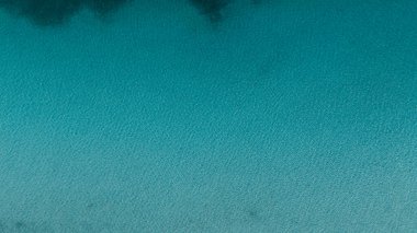 Derin mavi ve berrak Salda Gölü 'nün dokusunu gösteren hava görüntüsü. Minimalist ve barışçıl bir geçmişi var. Su yüzeyinde hafif dalgalanmalar var..