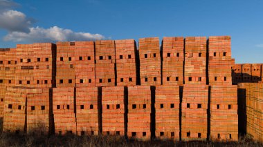 Kırmızı tuğlalar mavi gökyüzünün altında üst üste dizilmiş..