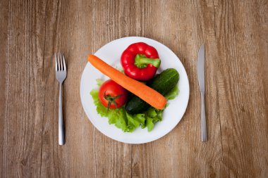 Sebze, çatal ve bıçak ahşap arka plan üzerinde beyaz tabak