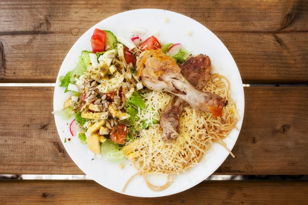 Plate with chicken pasta and green mixed salad.