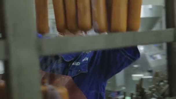 Planta de carne de trabajador para la producción de embutidos colgar productos para el tratamiento térmico . — Vídeo de stock