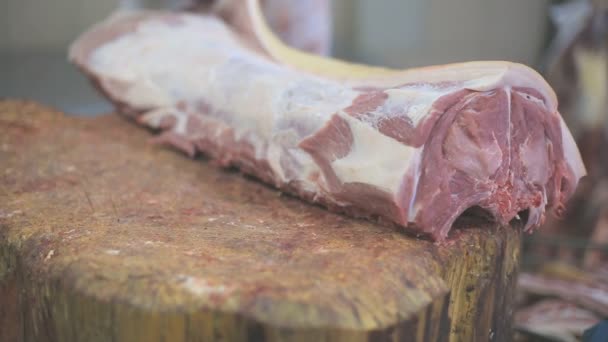 Slager gesneden varkenslende scheiden van de huid van vlees met een bijl. — Stockvideo