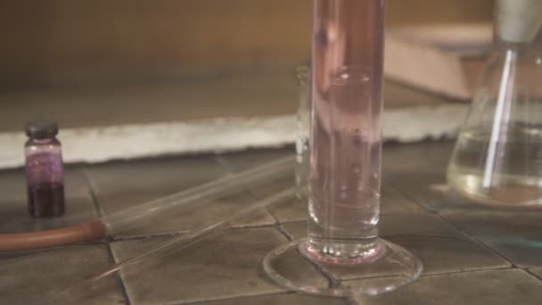 Na stole stojí chemické sklo a skleněné nádoby s nápisem v Latinské blízko nahoru. — Stock video