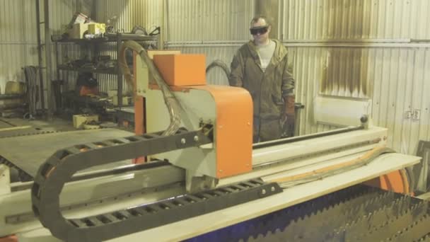 Worker in protective suit and glasses oversees work of plasma machine. — Stock Video