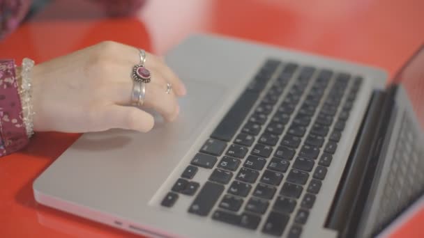 与圆环，年轻美丽女手推着红漆的表面的桌子上的触摸屏笔记本电脑上. — 图库视频影像