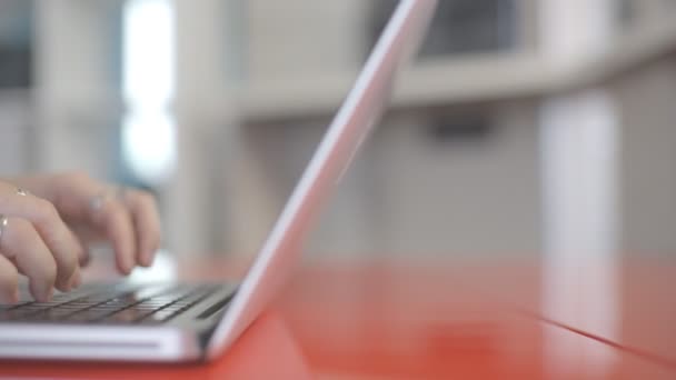 Womens händer med ringarna att skriva på en laptop tangentbord med suddig bakgrund. — Stockvideo