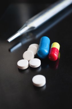 Farklı tıbbi hapları ve termometre 