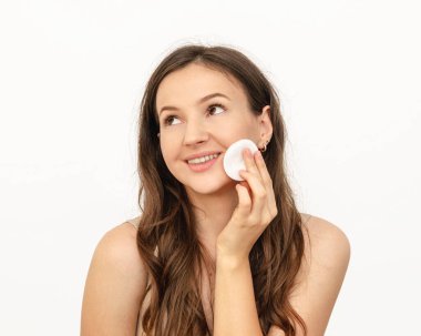 Genç ve güzel bir kadın yüzünü pamukla siliyor.