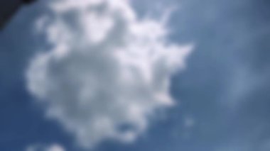 Mavi gökyüzünde soldan sağa hareket eden odak dışı beyaz bulutlar. Özgürlük gibi temaları temsil eden geçişler, geçişler ve kavramsal görüntüler için uygun.