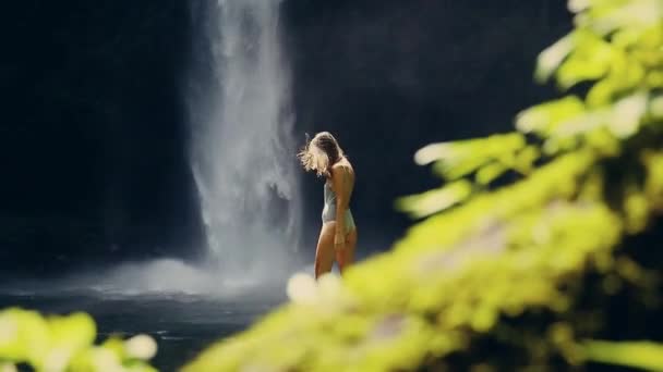 Mädchen vor einem Wasserfall mit einem Blatt — Stockvideo