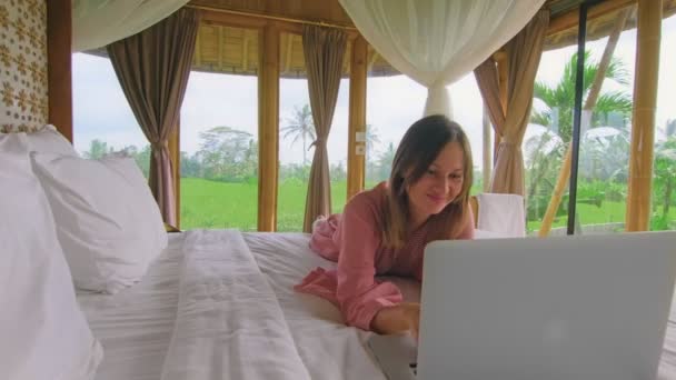 Jeune femme bavarder via Internet dans la maison de bambou écologique debout dans les rizières — Video