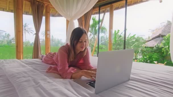 Jeune femme bavarder via Internet dans la maison de bambou écologique debout dans les rizières — Video