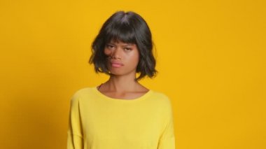 Mutsuz, ciddi, esmer tenli kadın sarı arka plana hayır diyor.