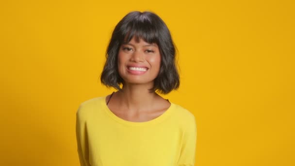 Оптимистичная темнокожая молодая женщина громко смеется на желтом фоне — стоковое видео