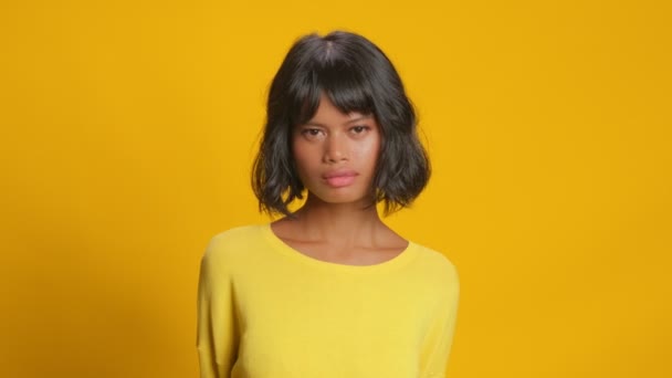 Dark skinned woman looks in disbelief at camera, says no indoor in yellow tones — Stock Video