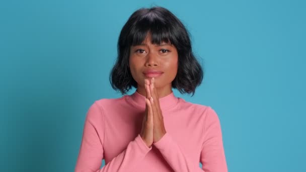 Hopeful miserable dark skinned woman keeps palms in pray asks for help — Stock Video