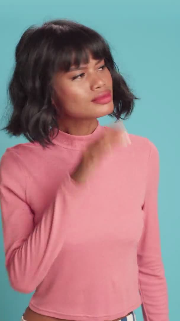 Young woman keeps hand near ear tries to overhear something over blue background — Stock Video