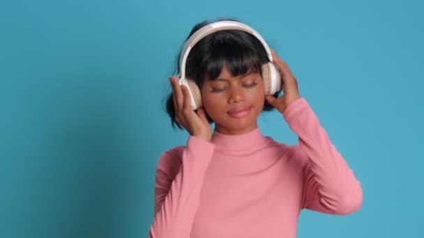 Молода жінка слухає меланхолійну музику в сучасних бездротових стерео навушниках — стокове відео