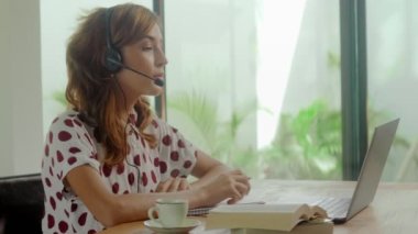 Kulaklık takan genç iş kadınının video görüşmesiyle iletişim kurması.