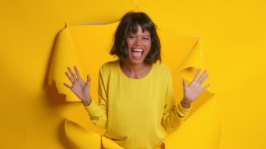 Koyu tenli mutlu kadın. İçtenlikle gülümsüyor. Yırtılmış delikten poz veriyor..