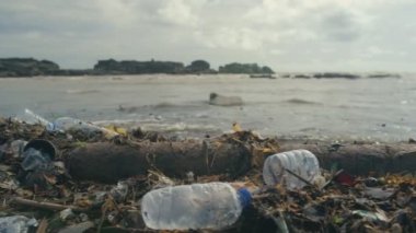 Plastik şişeler, torbalar ve okyanus sahilinin karanlık kumlarına atılmış diğer çöpler..