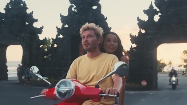 Young couple riding scooter together while happy woman keeping arms outstretched — Stock Video