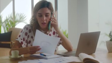 Ev bilgisayarında çalışan bir kadın müşteriye telefonla danışmanlık yapıyor.