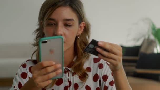 Žena zákazník drží kreditní kartu a smartphone sedí na gauči doma — Stock video