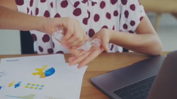 Junge Frau trägt Desinfektionsgel auf und reibt sich vor der Arbeit am Computer die Hände — Stockvideo