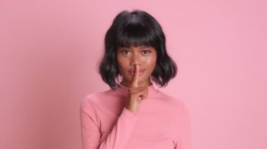 Kadın işaret parmağını dudaklara koyuyor kameraya hileli bir bakış atıyor.