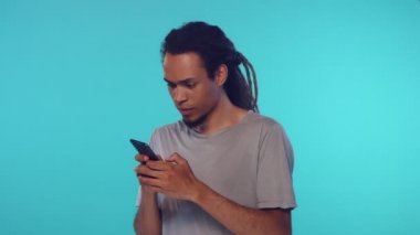 Şok olmuş Afrikalı Amerikalı adam gergin bir şekilde akıllı telefonuna mesaj yazıyor.