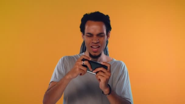 Africano americano cara detém smartphone horizontalmente, joga jogos online — Vídeo de Stock