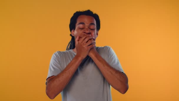 Aburrido joven africano cubriendo la boca mientras bosteza sobre fondo naranja — Vídeo de stock