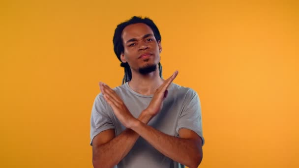 Angry young African man shows stop gesture, crossed hands over orange background — Stock Video