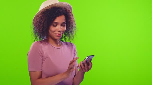 Escuro pele feminina tipos mensagem no telefone inteligente goza de comunicação on-line — Vídeo de Stock