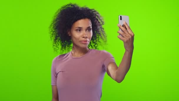 Afrikalı kadın modern akıllı telefondan selfie çekiyor. Mutlu bir ifadesi var. — Stok video